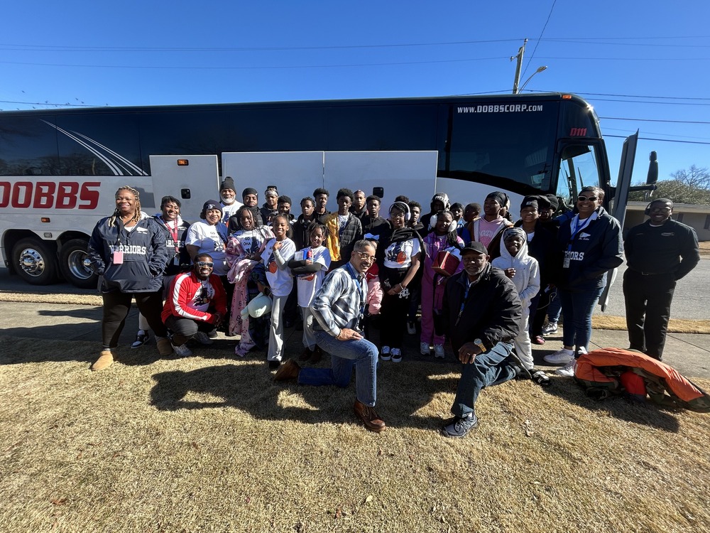 opelika chaperones basketball teams and cheer squad in front of a charter bus 